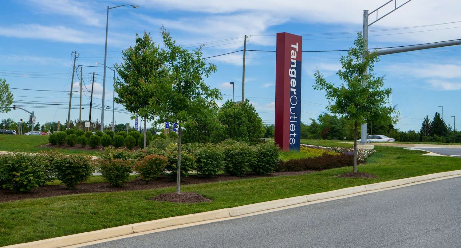 Tanger Outlets-sign entrance landscape bed bushes trees