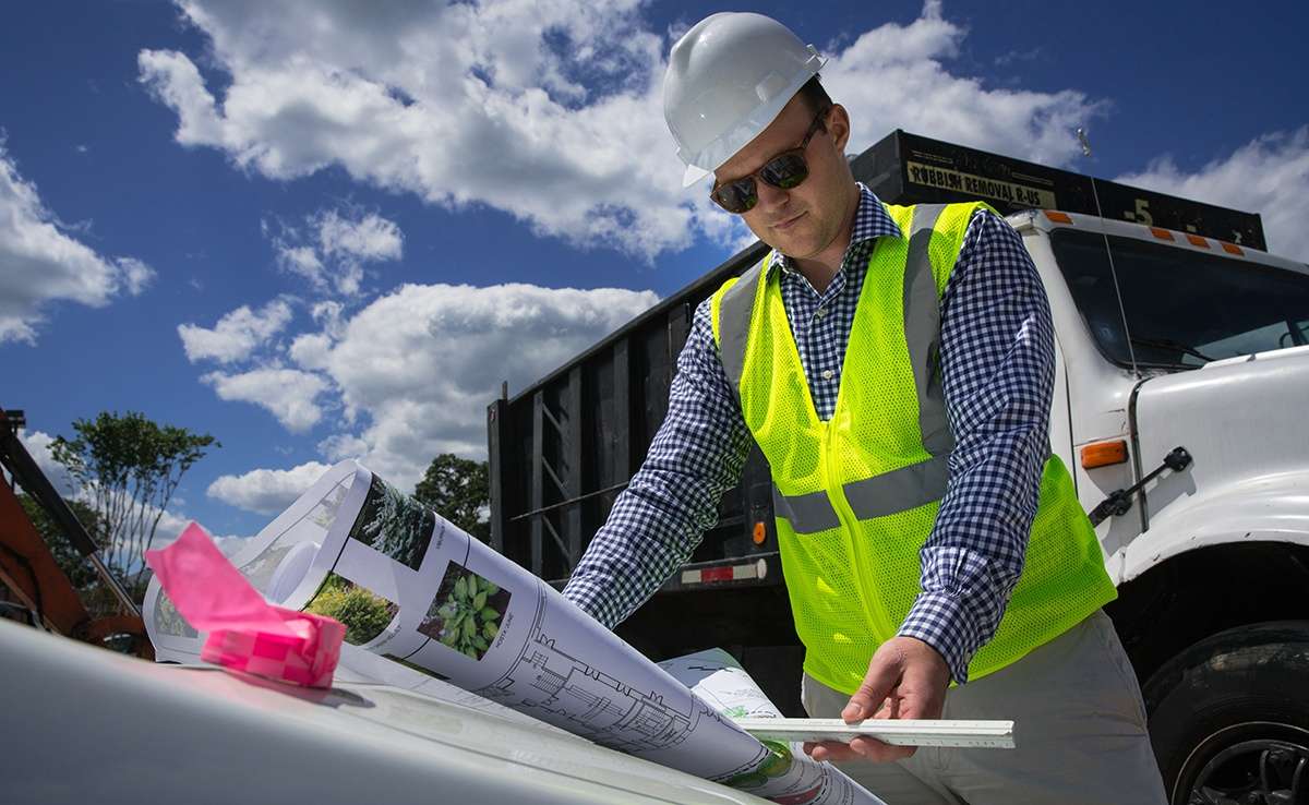 account manger looks at landscape design plans on hood of car